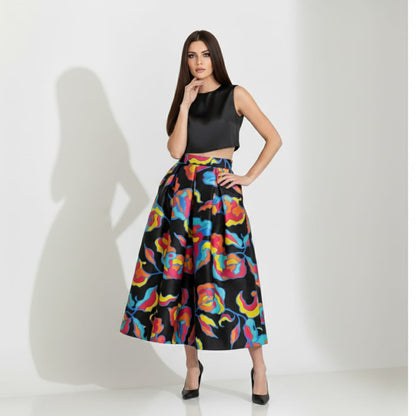 Woman wearing a black sleeveless top and colorful floral skirt on a white background