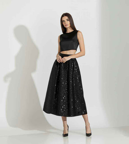Woman wearing a black sleeveless top and sequin skirt on a white background
