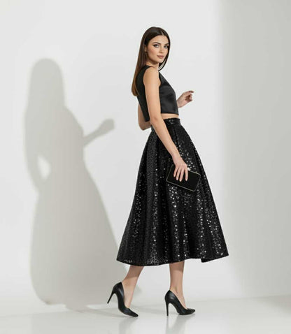 Woman wearing a black sequin skirt and top on a white background