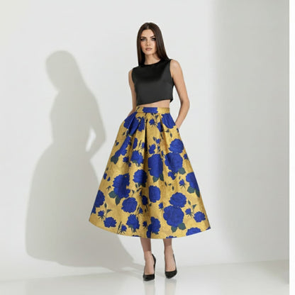 Woman wearing a black top and golden floral skirt on a white background