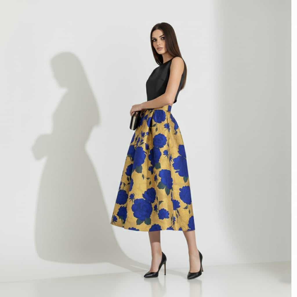 Woman wearing a black top and golden floral skirt on a white background