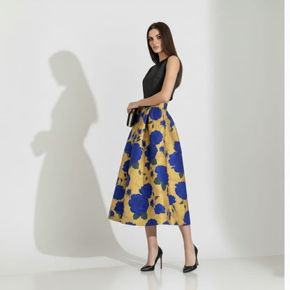 Woman wearing a black top and golden floral skirt on a white background