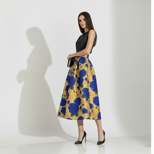Woman wearing a black top and golden floral skirt on a white background