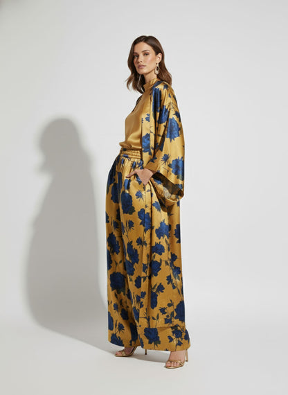 Woman wearing a golden kimono with blue floral pattern on a white background