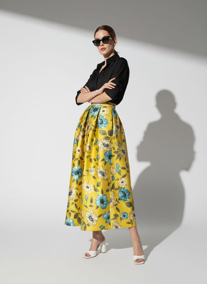 Woman wearing a black shirt and yellow floral skirt on a white background