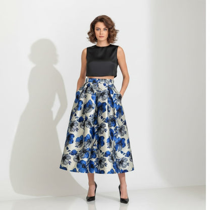 Woman wearing a black top and blue floral skirt on a white background